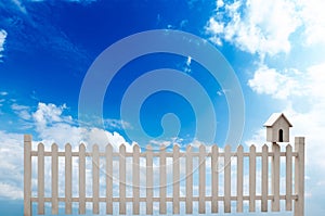 white fence with bird house and blue sky