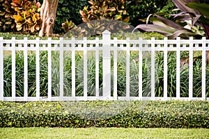 A white fence in front of a representative home