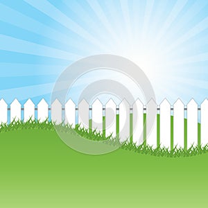 White fence and green grass on blue sky background