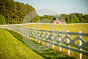 White fence leading up to a big red barn