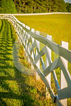 White fence leading up to a big red barn