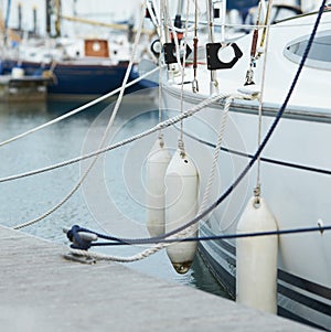 White fenders suspended between a boat and dockside for protection. Maritime fenders