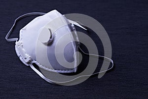 White ffp3 face mask with a valve on a dark background photo