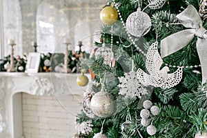 White fireplace decorated with candles and fir branches. Decorated Christmas tree. Classic apartments, morning in hotel