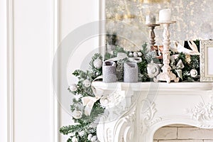 White fireplace decorated with candles and fir branches. Decorated Christmas tree. Classic apartments, morning in hotel