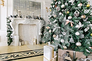 White fireplace decorated with candles and fir branches. Decorated Christmas tree. Classic apartments, morning in hotel