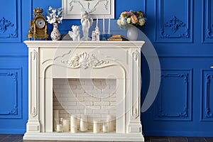 White fireplace with a mirror in the room, on the shelf watches, Souvenirs, candles