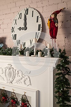 White fireplace with toy and wach face. Christmas decor. Close up. Selective focus