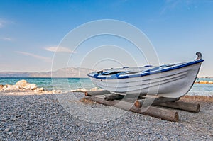 White fishing boat on sand with blue sky and water