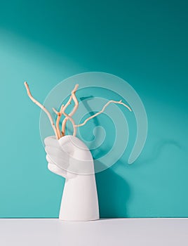 White fist holding dry branches against minty background.