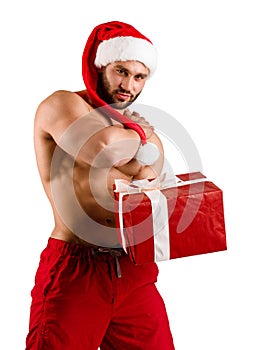 White fitness guy wearing Santa Claus hat with muschular body and big gift box with white stripe, isolated