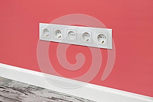 White five-way wall power socket on the pink wall