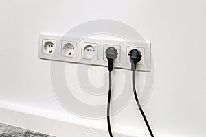 White five-way wall power socket on white wall