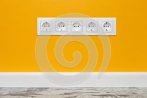 White five-way wall power socket on yellow wall