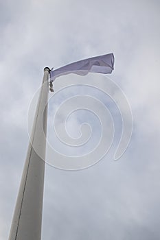 White flag on the mast near the beach. Flag on a background of cloudy sky