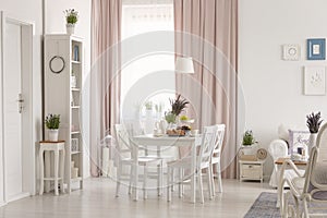 White flat interior with window with curtains, fresh lavender, dining table with breakfast and posters on wall in the real photo