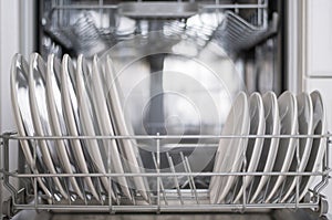 White flat plates are loaded into the dishwasher