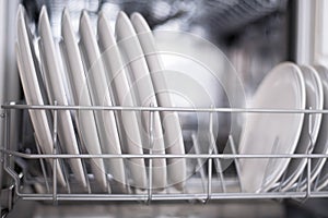 White flat plates are loaded into the dishwasher