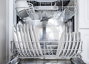 White flat plates are loaded into the dishwasher