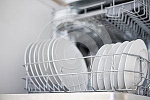 White flat plates are loaded into the dishwasher