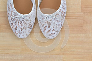 White floral lace ballet flat slip on shoes on wooden background