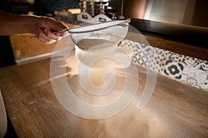 White flour sifted through a sieve before preparing pizza