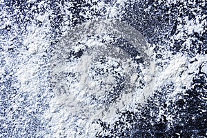 White flour sprinkled on a black textured table