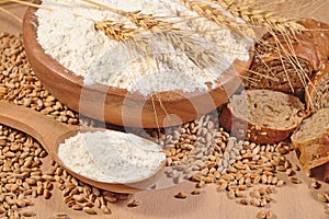 White flour in a wooden spoon, wheat and bread