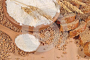 White flour in a wooden spoon, wheat and bread