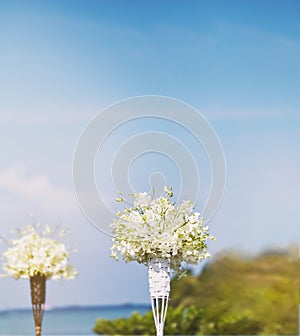 White flower bouquet on the bamboo vase decoration in beach wedding venue, blurry background