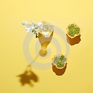 White flower in the glass bottle and kawani fruit against yellow background