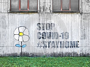 White flower on wall with message STOP COVID
