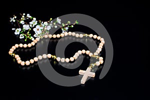 white flowers on black background and wooden rosary