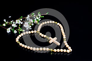white flowers on black background wooden rosary