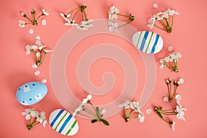 White flowers, cherry blossoms and Easter eggs with blue stripes on a pink background. Easter background, copy space