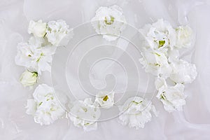 White flowers of eustoma, lisianthus, on a white silk fabric background