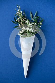 White flowers in paus tracing paper cone on blue background photo