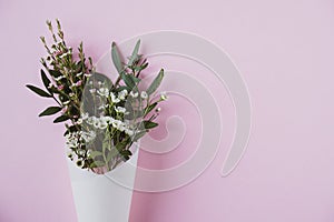 White flowers in paus tracing paper cone on pink background photo