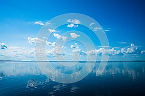 White fluffy clouds blue sky above a surface of the sea