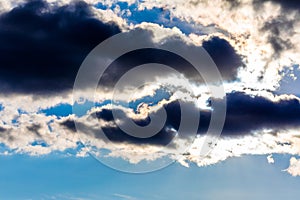 White fluffy clouds in the blue sky. Dramatic cloudscape with sun rays