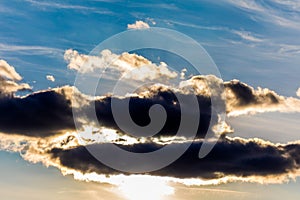 White fluffy clouds in the blue sky. Dramatic cloudscape with sun rays