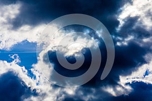 White fluffy clouds in the blue sky. Dramatic cloudscape with sun rays