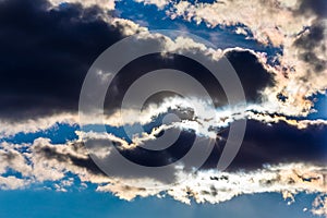 White fluffy clouds in the blue sky. Dramatic cloudscape with sun rays