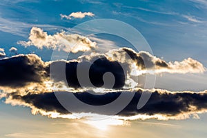 White fluffy clouds in the blue sky. Dramatic cloudscape with sun rays