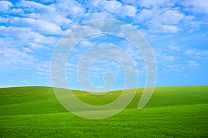 White fluffy clouds in the blue sky and green hills. Summer or spring meadow nature