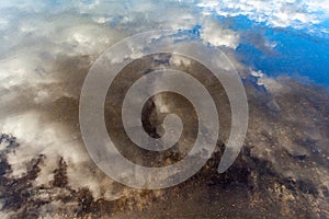 White fluffy clouds with blue sky reflecting on river water surf photo