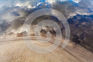 White fluffy clouds with blue sky reflecting on river water surf photo