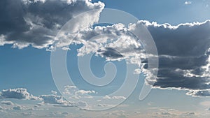 White fluffy clouds slowly float through the blue daytime sky timelapse