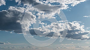 White fluffy clouds slowly float through the blue daytime sky timelapse