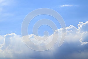 White fluffy large cumulus clouds in the vastness of a light blue sky under the rays of a bright sun in the morning